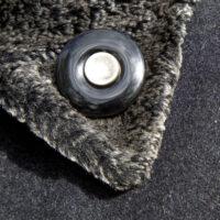 Onyx Trauerknopf mit einem Knopf eines geliebten Menschen wird als Reversnadel an einem dicken Wintermantel getragen.